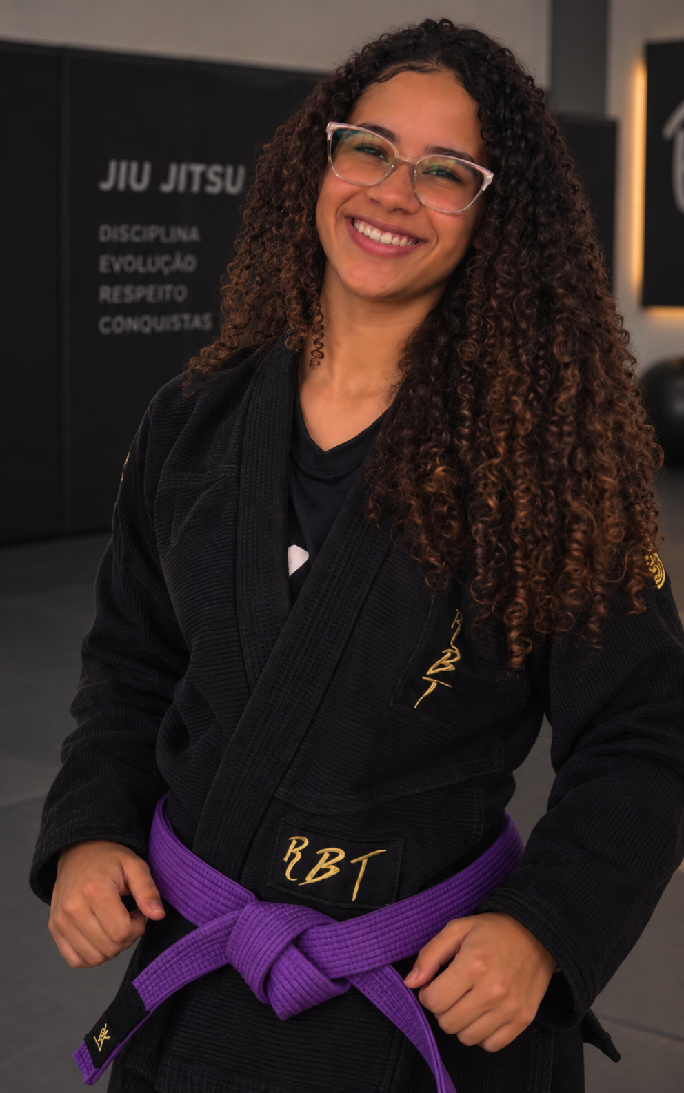Bárbara de kimono preto e faixa roxa em uma academia de Jiu-Jitsu